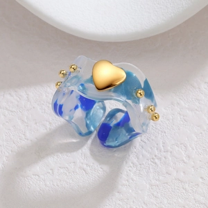 Blue resin heart ring with gold accents and ink texture on a textured white background
