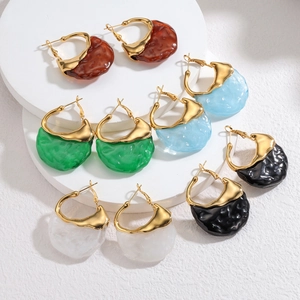 Close-up of irregular wave earrings in five resin colors on a white tiered display