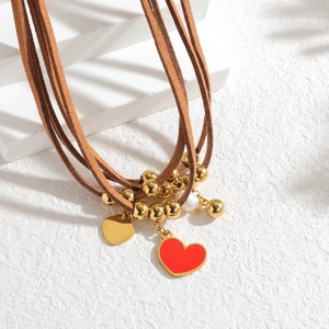 Gros plan de cordons en daim marron avec pendentif cœur rouge et perles dorées