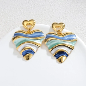 Boucles d'oreilles cœur dorées avec émail à vagues bleues et vertes sur socle blanc