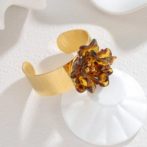 Detail of 18k gold plated open cuff bangle with amber resin leopard print flower charm