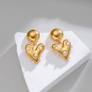 Boucles d'oreilles cœur en or 18k avec perles sur présentoir en pierre blanche