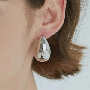 Minimalist silver teardrop earrings with high-polish metallic finish worn by a model