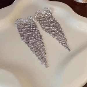 Detailed view of silver tassel drop earrings with sparkling cubic zirconia on ceramic tray