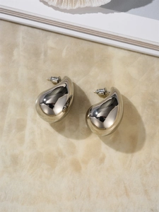 Detailed view of polished silver water drop earrings on a marble textured surface