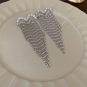 Elegant silver tassel earrings with sparkling crystals displayed on a ceramic tray