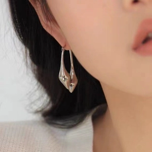 Minimalist silver teardrop earrings with a fluid streamlined design worn by a model
