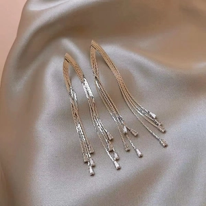 Elegant long tassel drop earrings with sparkling rhinestones on champagne silk fabric