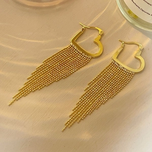 Detail of elegant gold heart-shaped long tassel earrings with delicate beaded chains
