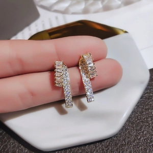 Boucles d'oreilles géométriques dorées avec zircons sertis sur plateau en marbre blanc