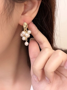 Detailed view of pearl cluster grape earrings with gold-toned metal accents on a model