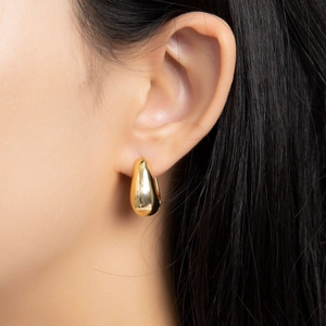 Eleganti orecchini a goccia in oro con design aerodinamico lucido indossati da un modello