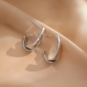 Detail of silver double-layered crossover earrings on elegant champagne satin fabric
