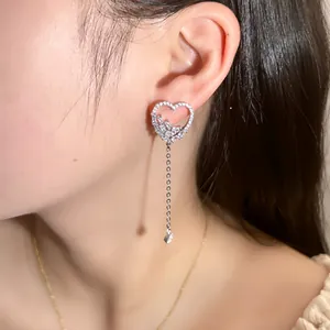 Elegant silver heart tassel earrings with rhinestones on a female model profile view