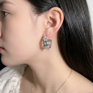 Silver C-shaped hoop earrings with liquid metal texture on female model ear