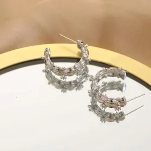 Macro shot of silver C-shaped wave textured hoop earrings on a mirror tray display
