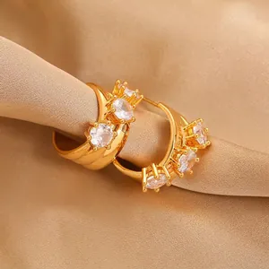 Macro shot of gold hoop earrings with sparkling cubic zirconia on a silk background