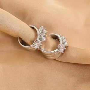 Macro detail of silver hoop earrings with clear cubic zirconia on champagne silk fabric