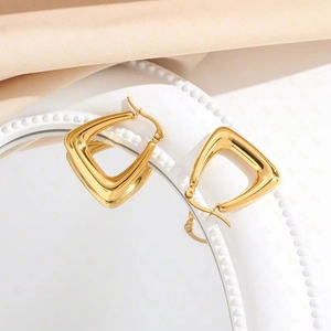 Boucles d'oreilles triangulaires minimalistes en acier inoxydable doré sur un plateau