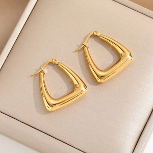 Boucles d'oreilles triangulaires en acier inoxydable doré sur une boîte à bijoux beige