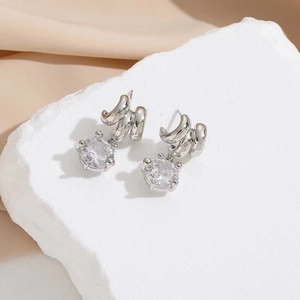 Elegant 18k silver plated earrings featuring a round zircon on a white stone and silk background