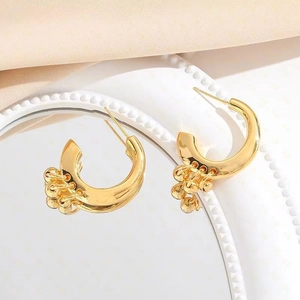 Chic gold-plated C-shaped hoop earrings with hanging metal beads on white textured disk