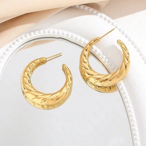 Golden hollow hoop earrings with spiral twist texture shown in a minimalist setting