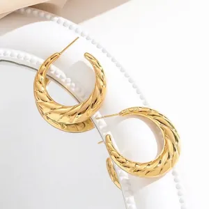 Golden hollow croissant hoop earrings with spiral texture on white pearl tray