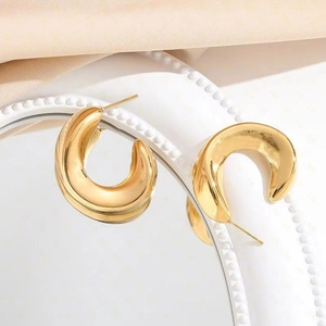 Polished 18K gold plated chunky C-shape wave earrings on a decorative tray