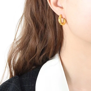 Polished 18K gold plated wavy C-shape hollow hoop earrings worn by a model