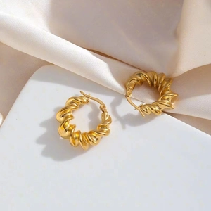 Vintage golden twisted croissant C-shape hoop earrings on elegant white silk background