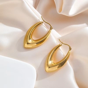 Detailed view of polished 18k gold plated U-shaped drop earrings on elegant silk fabric