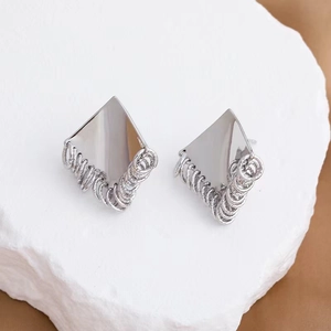 Minimalist silver diamond and circle tassel earrings on white stone textured surface