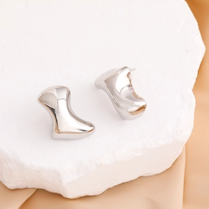 Boucles d'oreilles irrégulières minimalistes polies sur un fond de pierre