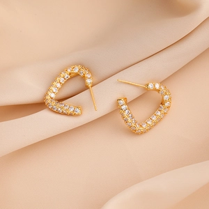 Golden heart-shaped hoop earrings with sparkling pavé zircon on silk fabric