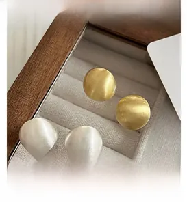 Vue macro de boucles d'oreilles boules minimalistes avec texture métal brossé mat