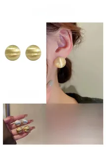 Détail des boucles d'oreilles boules rondes en métal brossé mat, dorées et argentées
