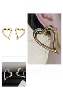 Detailed view of oversized hollow heart hoop earrings in polished gold and silver finishes