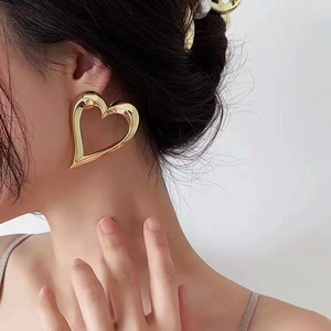 Minimalist exaggerated heart-shaped earrings with high-polish gold finish on model