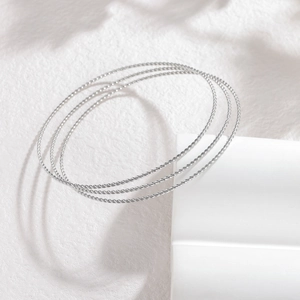 Détails macro d'un ensemble de bracelets argentés torsadés au fini tressé