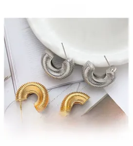 Detailansicht goldener und silberner C-förmiger Creolen mit strukturiertem Spiraldesign