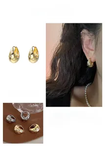 Macro view of teardrop metal hoop earrings with engraved stars and zircon stone insets