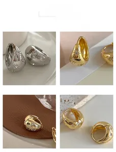 Detail showing polished star-patterned oval hoop earrings with sparkling zircon inlay