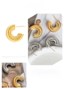 Makroaufnahme von C-förmigen Ohrringen mit Spiralgewindetextur in Gold und Silber