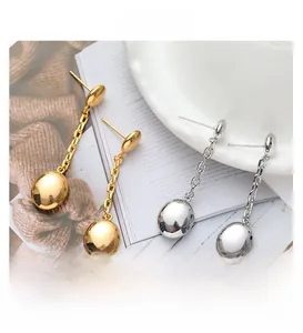 Close-up of gold and silver tassel earrings with glossy oval studs and chain tassels