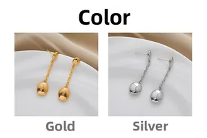 Detail view of gold and silver chain tassel earrings on white plate and silk background