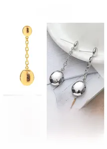 Detail of minimalist gold and silver drop earrings with spherical studs and long link chains
