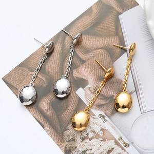 Elegant gold and silver long tassel earrings with polished oval drops on an open magazine