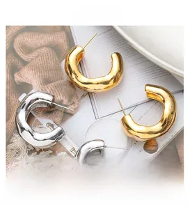 Detailed view of chunky C-shape twisted metal hoop earrings in gold and silver finish