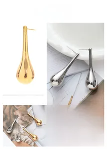 Detailed macro view of long teardrop metal earrings with mirror polished finish
